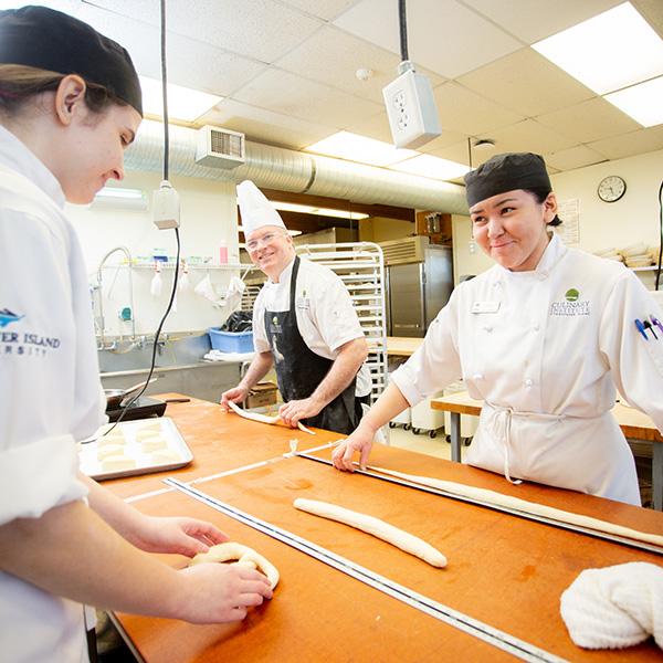 Three baking students making rolls